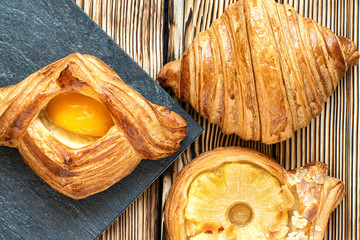 golden buns with peach and pineapple, closeup, on a wooden table, flat lay. homemade baking. light breakfast in the cafe. croissants with fruits in a pastry shop
