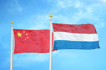 Fototapeta na wymiar China and Netherlands two flags on flagpoles and blue cloudy sky