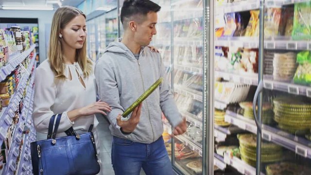 Portrait of young woman and man buying frozen pizza at grocery store