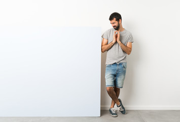 Young handsome man with beard holding a big blue empty placard scheming something