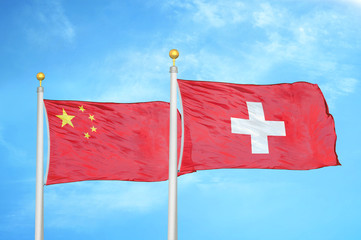 China and Switzerland two flags on flagpoles and blue cloudy sky