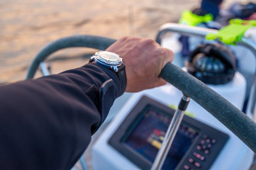 Skipper's arm at the helm and sailing boat navigation equipment. Scotland waters.