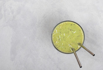 Vegan drink smoothie from kiwi, banana and rucola in a glass on a light background top view