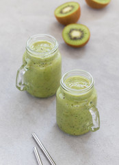 Green drink smoothie from kiwi, banana and rucola in a jar on a light background