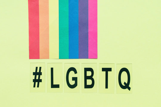 Rainbow flag, hashtag symbol and letters LGBTQ on yellow background, copy space