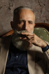 Portrait of an attractive bearded business man with a cigar in a dark room.