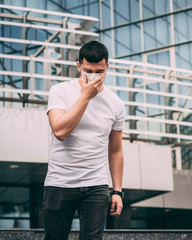 a man in a white T-shirt. a man in a white mask on his face. sneezes behind his hand