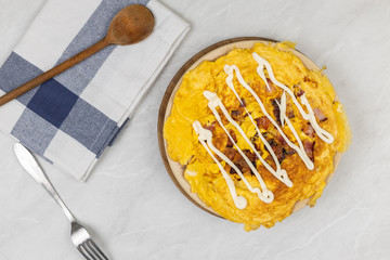 Flatlay above fried omelet with bacon and mayonnaise served on marble background