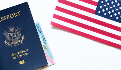 American passport with permanent resident card (green card) and United States flag on white...