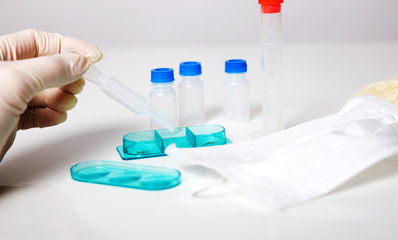 Fototapeta premium tube chemical dropper and mask in a laboratory on white grey background, hand in gloves