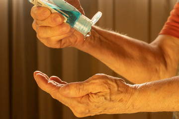 Older caucasian woman applying alcohol gel cleaning hands to helping protect from coronavirus covid-19