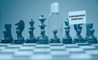 Coronavirus concept image chess pieces and hand sanitizer on chessboard illustrating global struggle against novel covid-19 outbreak with coronavirus strategy sign.