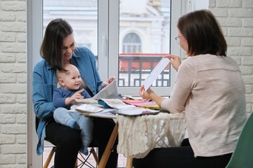 Woman designer and mother with baby choosing fabrics for curtains