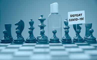 Coronavirus concept image chess pieces and hand sanitizer on chessboard illustrating global struggle against novel covid-19 outbreak with defeat covid-19 sign.