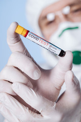 Microbiologist with a tube of biological sample contaminated by Coronavirus with label Covid Test....