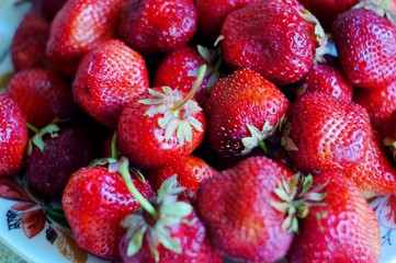 A plate filled with ripe red strawberries.