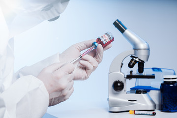 The doctor gets the cure into the syringe. Glass medical bottle in a doctor's hand. A bottle with a...