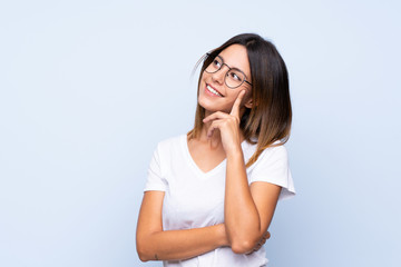 Young woman over isolated blue background with glasses