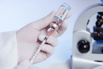 The medic gets the vaccine into the syringe. Glass medical bottle in a doctor's hand. A bottle with...