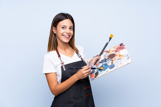 Young woman over isolated blue background holding a palette