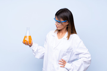 Young woman over isolated blue background with a scientific test tube