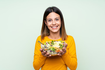 Young woman with salad over isolated green wall