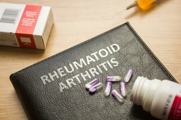 Book about Rheumatoid Arthritis and medication, injection, syringe and pills