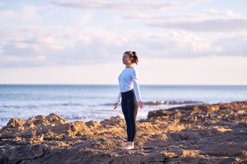 Young beautiful sportwoman practicing yoga. Coach teaching mountain pose at the beach