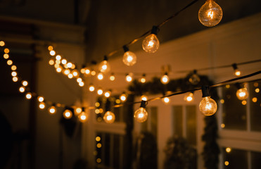 Luminous incandescent lamps hang in the form of a garland on wires, against the background of a...