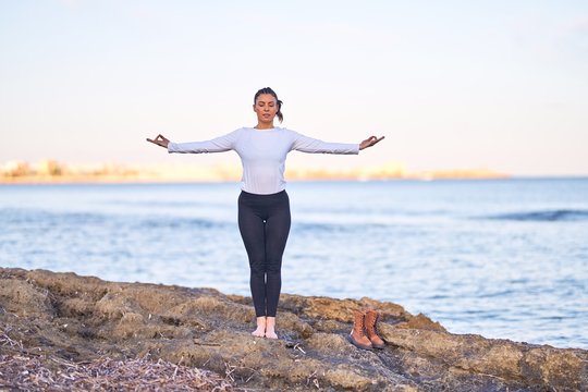 Young beautiful sportwoman practicing yoga. Coach teaching mountain pose at the beach