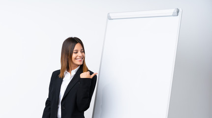 Young woman giving a presentation on white board pointing to the side to present a product