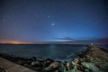 Long exposure of Baltic sea with scenic colorful sunset. Silky water motion and breakwater with huge rocks. 