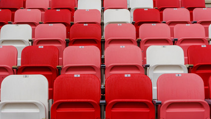 Empty red and white plastic seats with numbers at the stadium. Sport concept.
