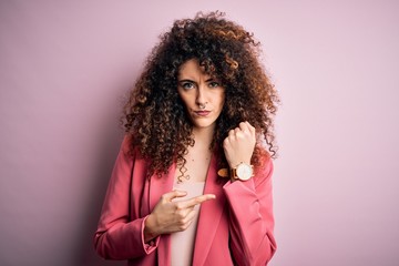 Young beautiful businesswoman with curly hair and piercing wearing elegant jacket In hurry pointing...