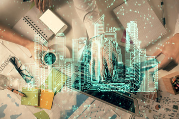 Double exposure of man and woman working together and the buildings hologram drawing. Computer background. Top View. Smart city concept.