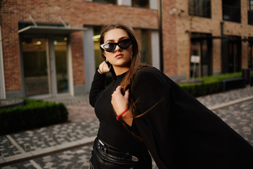 Gorgeous girl walks about the city. Brunette with long hair in a black dress and leather. Girl, fashion photo, street fashion. The model walks around the city of Europe, travels.