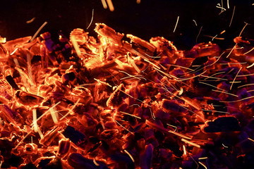 Fototapeta na wymiar Burning firewood in the fireplace close up, BBQ fire, charcoal background. Charcoal fire with sparks