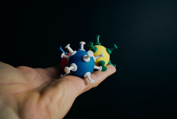 One hand has some models of coronavirus on a black background with copyspace