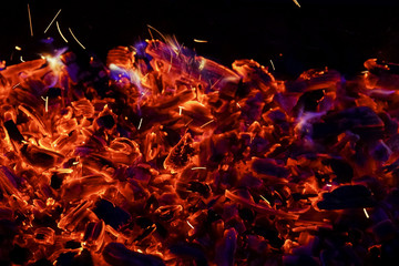 Fototapeta na wymiar Burning firewood in the fireplace close up, BBQ fire, charcoal background. Charcoal fire with sparks