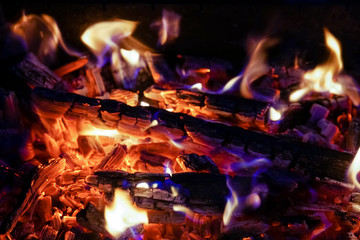 Burning firewood in the fireplace close up, BBQ fire, charcoal background. Charcoal fire with sparks