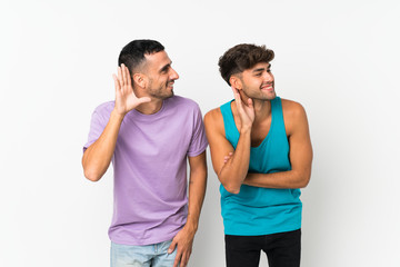 Fototapeta premium Two men over isolated background listening to something by putting hand on the ear