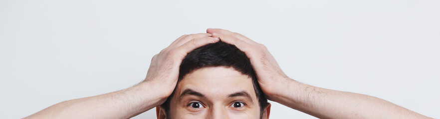 Young excited man touching head with hands over white studio background