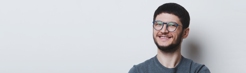 Fototapeta premium Portrait of smiling young man with glasses over white studio background