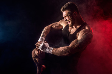 Sport concept. Sportsman muay thai boxer fighting on black background with smoke. Copy Space.