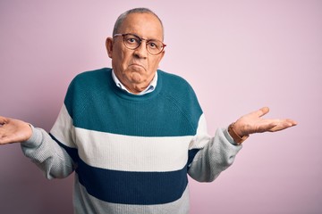 Senior handsome man wearing casual sweater and glasses over isolated pink background clueless and...