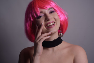 A bright girl with bright pink hair rejoices, goes crazy, has fun, grimaces. Positive energy. Summer mood. The girl smiles and laughs sincerely, an informal beauty. Black dress.