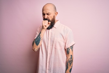 Handsome bald man with beard and tattoo wearing casual shirt over isolated pink background feeling unwell and coughing as symptom for cold or bronchitis. Health care concept.