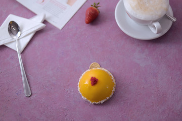 Photo of breakfast on a pink background. Latte coffee and a chic yellow dessert in coconut. Dessert spoon. Elegant layout of food. Diet, sweets.
