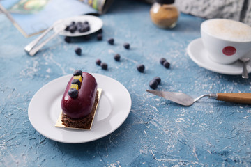 beautiful red burgundy dessert with blueberries. Blueberries on a plate. Coffee latte breakfast. Layout on a blue creative background. Gorgeous photo of breakfast, sweets. Training food photo.