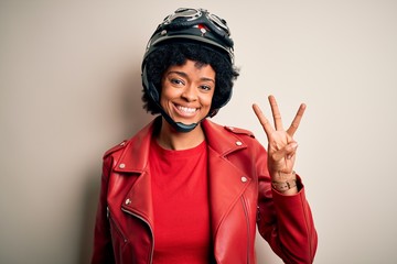 Young African American afro motorcyclist woman with curly hair wearing motorcycle helmet showing and pointing up with fingers number three while smiling confident and happy.